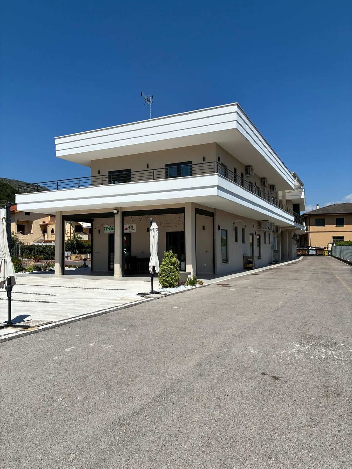 Un bâtiment à deux étages, doté d’un toit plat, d’un espace d’entrée abrité et d’un petit jardin.