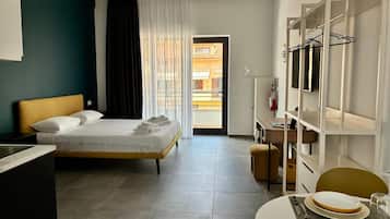 Une chambre d’hôtel comprenant un lit, un bureau, une chaise, une table à manger pour deux personnes et une armoire avec un espace pour suspendre les vêtements.