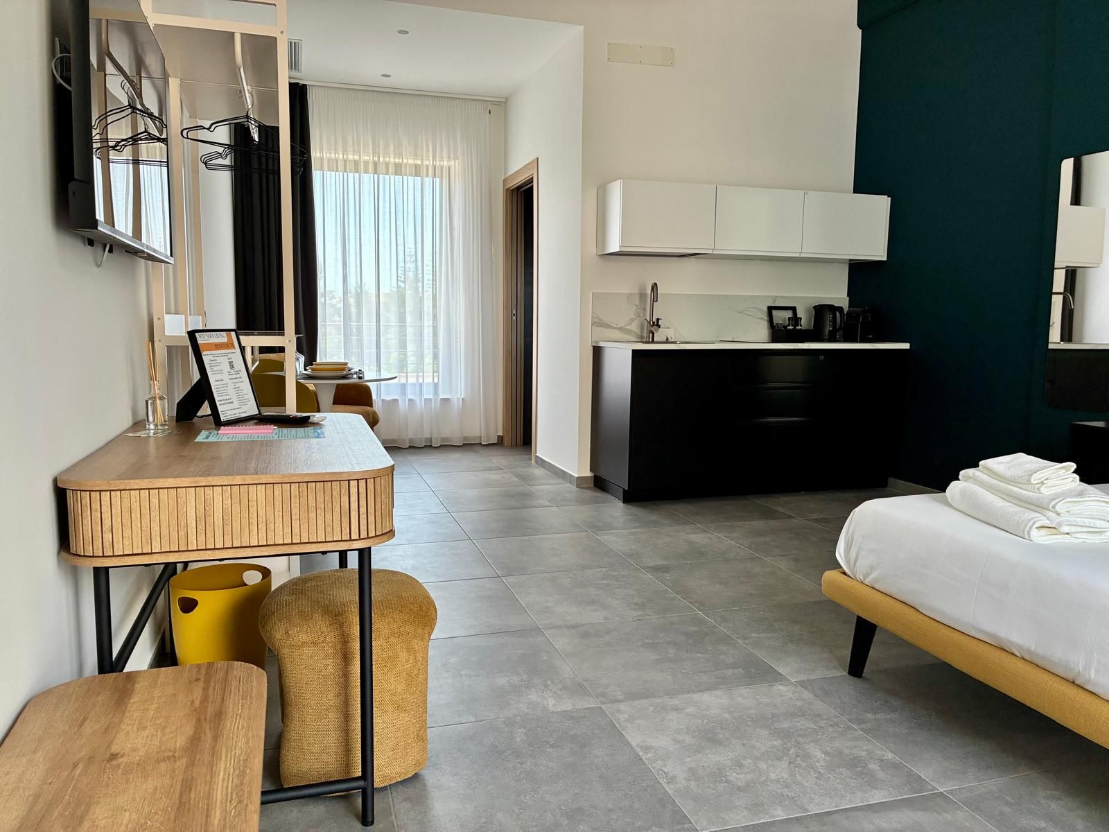 Une chambre d’hôtel comprenant un lit, un bureau, une chaise, une petite table, un coin cuisine et une salle de bain.
