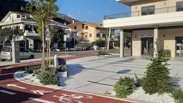 Calle con un carril bici rojo, un paso de peatones y un edificio con un letrero que dice 'Piazza Ria'.