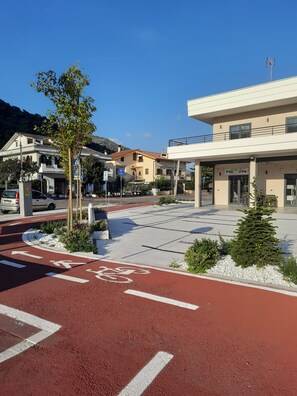 En gata med en röd cykelbana, ett övergångsställe och en byggnad med en skylt som visar texten ”Piazza Ria”.
