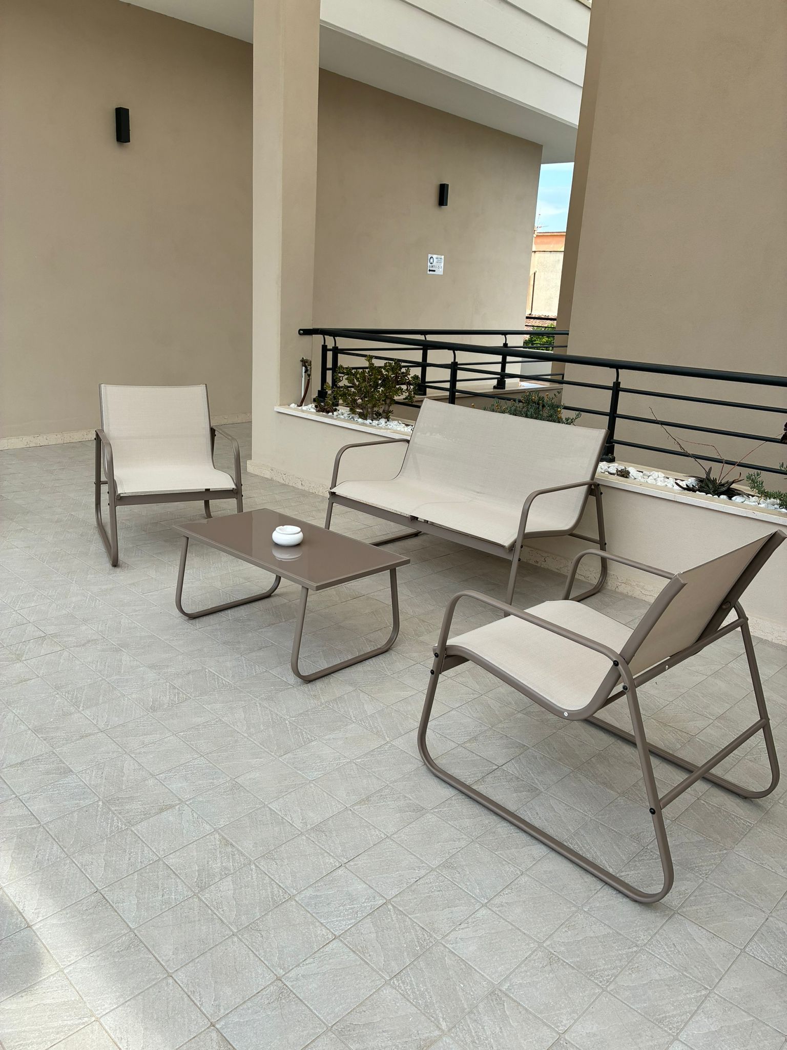 Un espace extérieur aménagé avec une table, deux chaises, un banc et une rambarde.