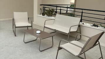 Un espace extérieur aménagé avec une table, deux chaises, un banc et une rambarde.