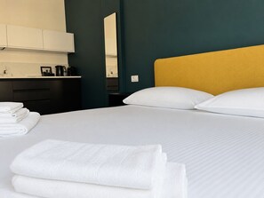 Ett hotellrum med en säng, kuddar och prydligt hopvikta handdukar.