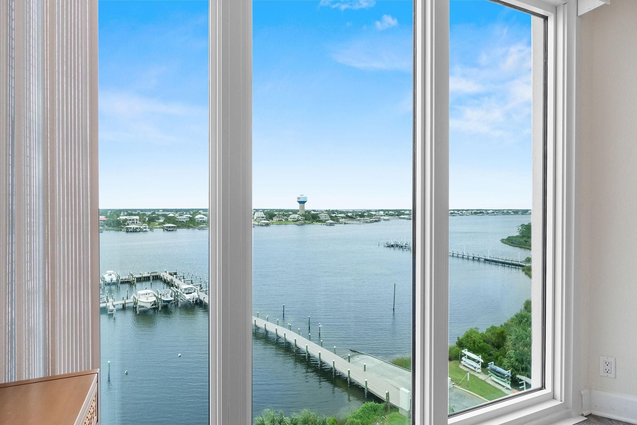 Blick aus einem Fenster auf eine Marina mit vor Anker liegenden Booten, einem Wasserturm und einer Brücke.