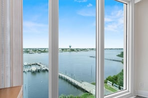 Blick aus einem Fenster auf eine Marina mit vor Anker liegenden Booten, einem Wasserturm und einer Brücke.