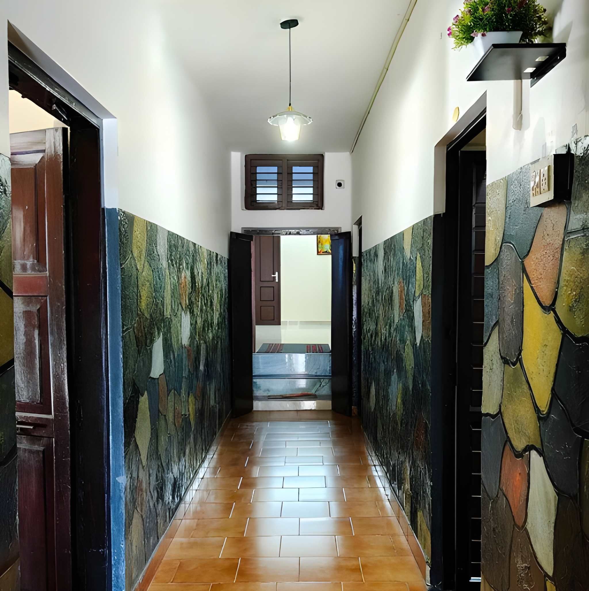 Un pasillo con piso de baldosas, una lámpara en el techo y una puerta que da a una habitación.