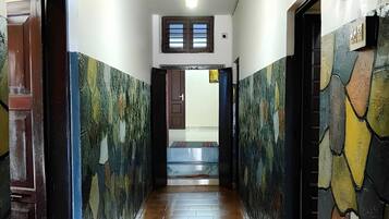 Un pasillo con piso de baldosas, una lámpara en el techo y una puerta que da a una habitación.