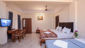 A hotel room with a bed, a desk, a television, and a painting on the wall.