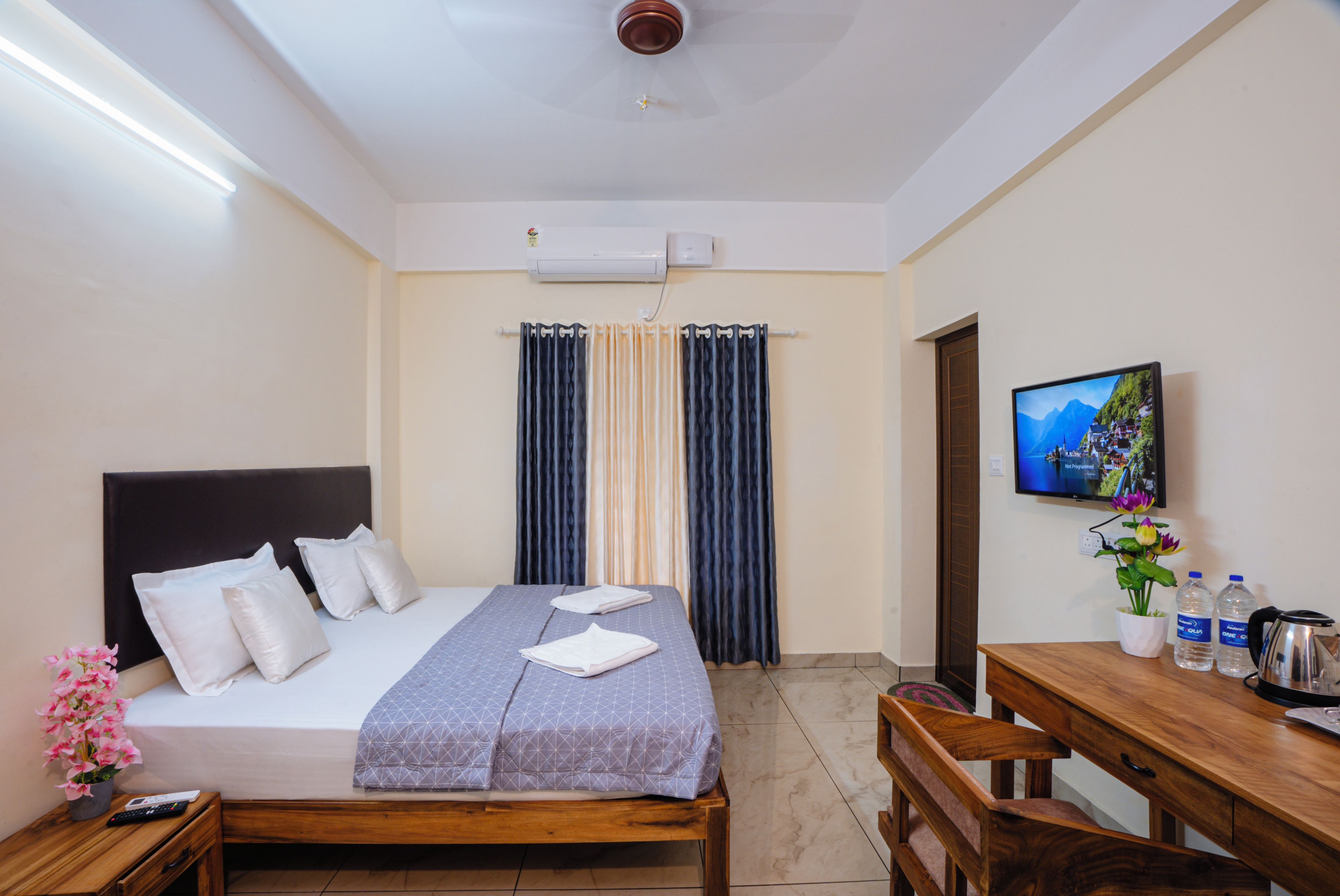 A hotel room with a bed, a desk, a television, and a window with curtains.