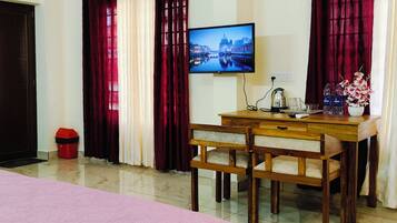 A hotel room with a bed, a desk with a chair, a television, and curtains.