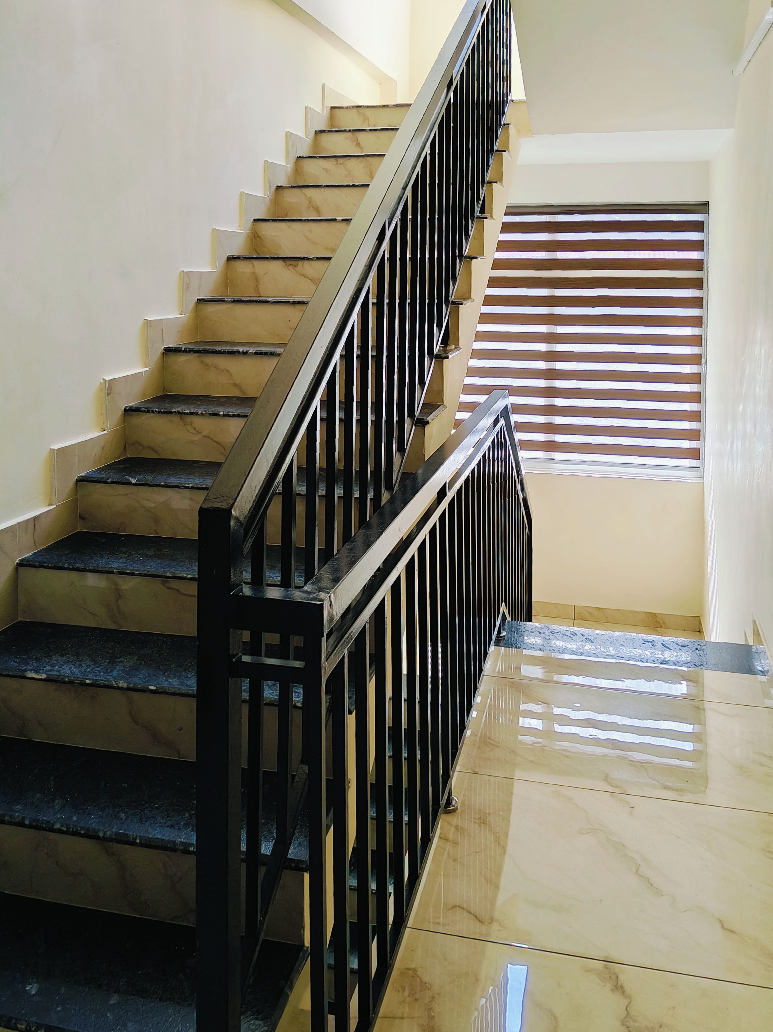 A staircase with black railings and marble steps leading to a landing.