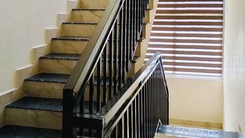 A staircase with black railings and marble steps leading to a landing.