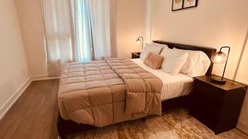 A bedroom with a bed, nightstands, a rug, and a window with curtains.