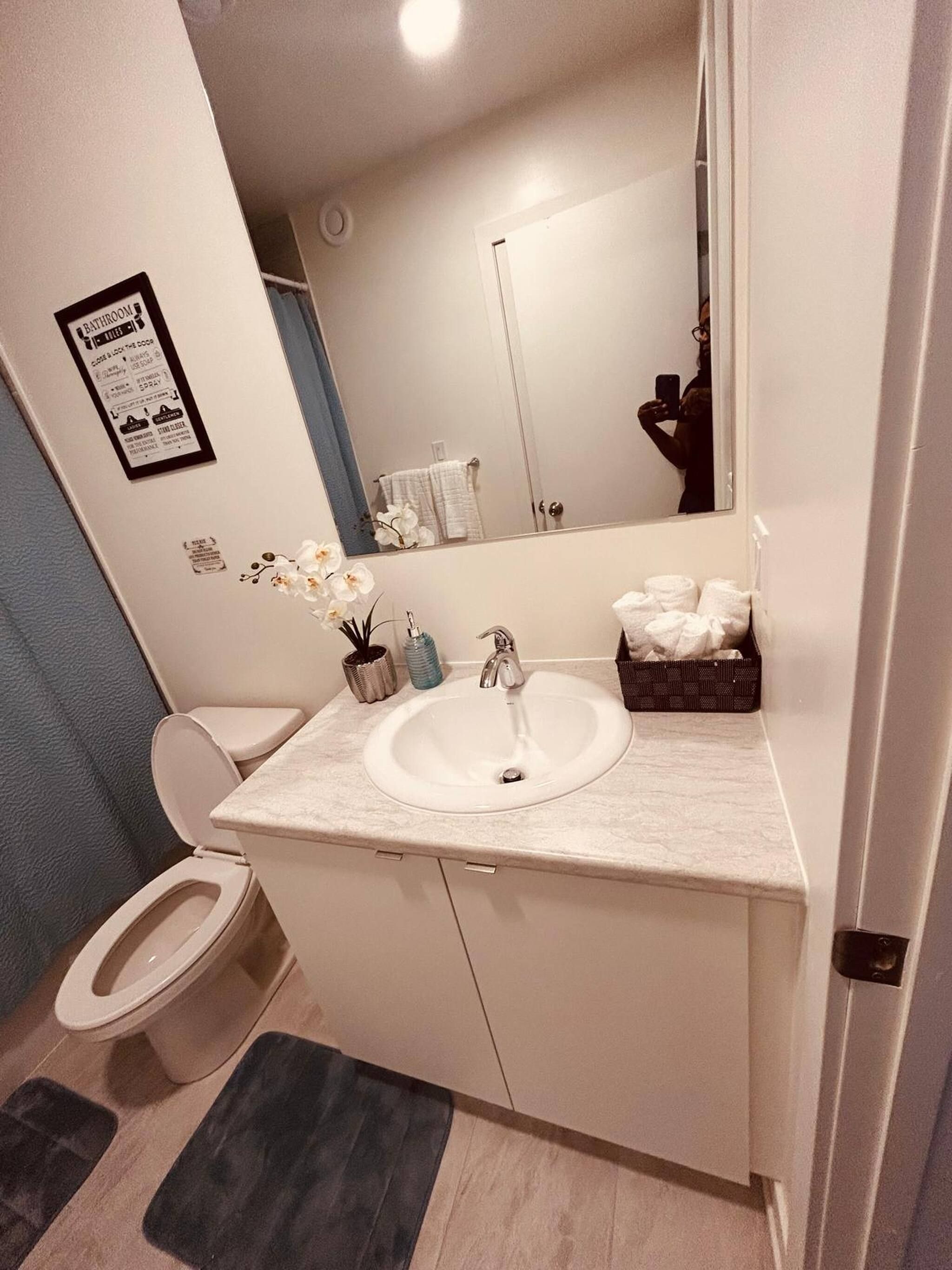 A bathroom with a white sink, a toilet, a mirror, and a blue wall.