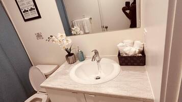 A bathroom with a white sink, a toilet, a mirror, and a blue wall.