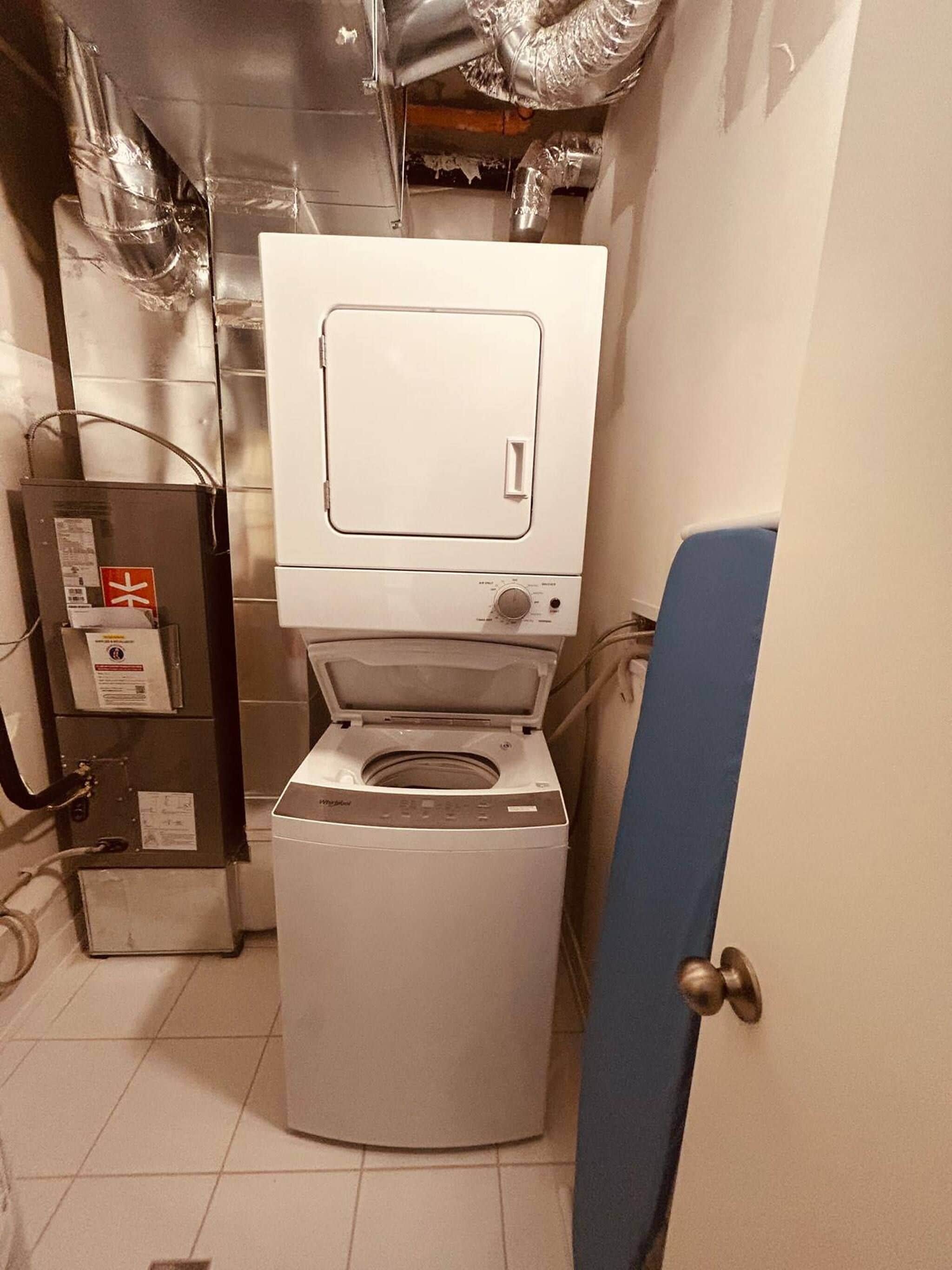 A compact, modern bathroom with a white toilet, a visible water heater, and a blue door.