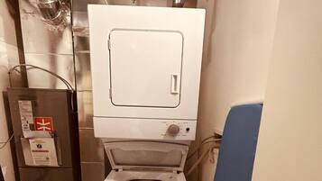 A compact, modern bathroom with a white toilet, a visible water heater, and a blue door.