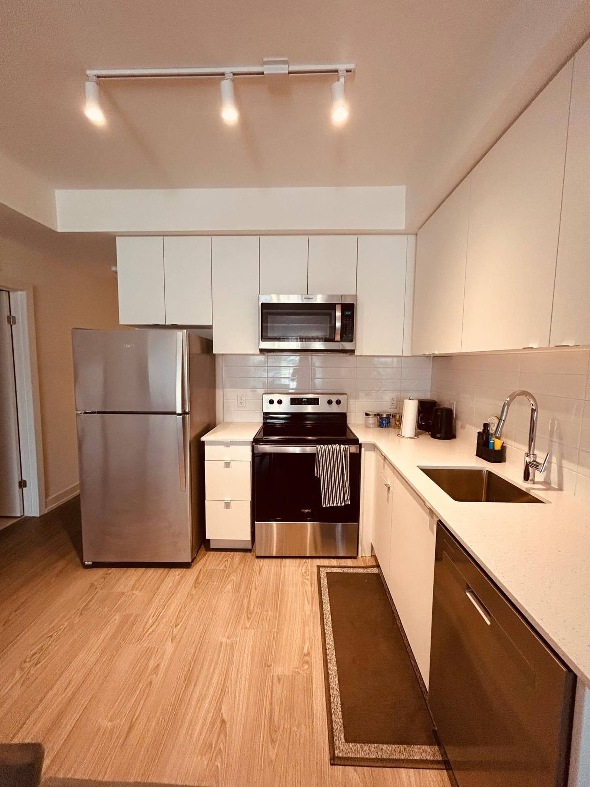 A modern kitchen with stainless steel appliances, a microwave, oven, and a sink.