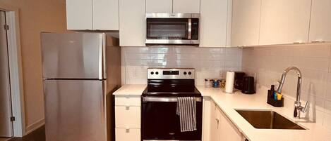 A modern kitchen with stainless steel appliances, a microwave, oven, and a sink.