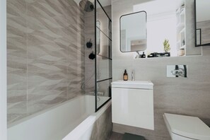 A modern bathroom with a glass-enclosed shower, a white sink, and a toilet. - Saturn Studio by Navie Stays (Poole)