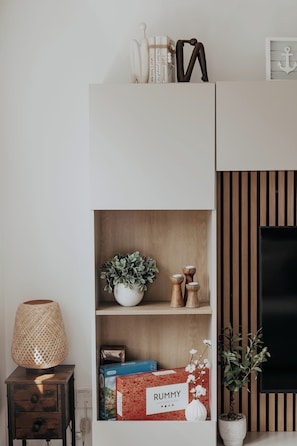 A modern living room with a bookshelf, a small table with a lamp, and a potted plant. - Coastal Hideaway by Lil Blu Stays (Bournemouth, Christchurch and Poole)