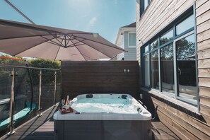 A hot tub with a wooden deck, a glass enclosure, and a large umbrella. - Harbour View by Navie Stays (Poole)