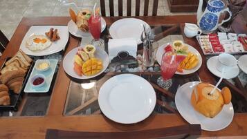 A dining table set with breakfast items including toast, eggs, fruit, and beverages.