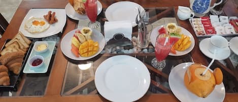 A dining table set with breakfast items including toast, eggs, fruit, and beverages.