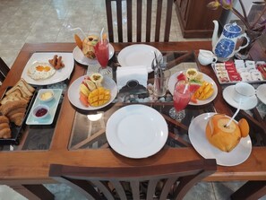 A dining table set with breakfast items including toast, eggs, fruit, and beverages.