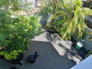 Un giardino pensile con piante in vaso, un’area relax e una fontana.