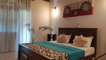 Un dormitorio con cama, mesita de noche, lámpara de pared y una obra de arte decorativa con un motivo de sol.