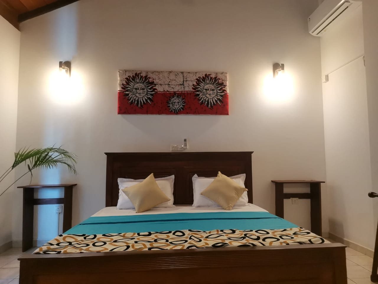Un dormitorio con una cama de madera, dos mesitas de noche, una obra de arte colgada en la pared y una planta en maceta.