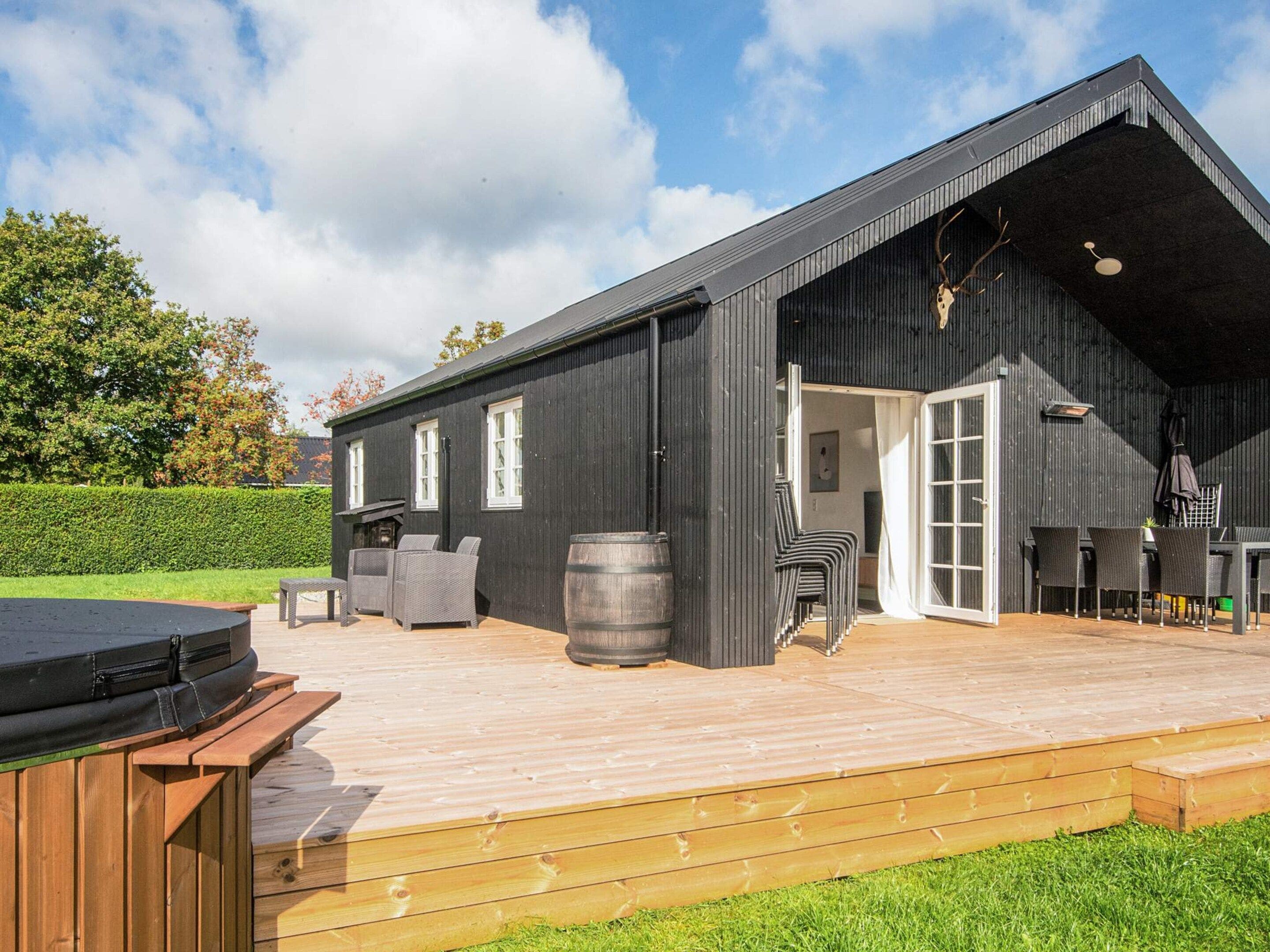 A modern building with a large deck, outdoor seating, and a barbecue area.