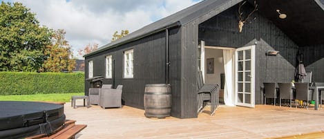 A modern building with a large deck, outdoor seating, and a barbecue area.