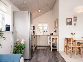 A compact kitchen with a refrigerator, stove, and sink, a dining area with a table and chairs, and a window with a view.