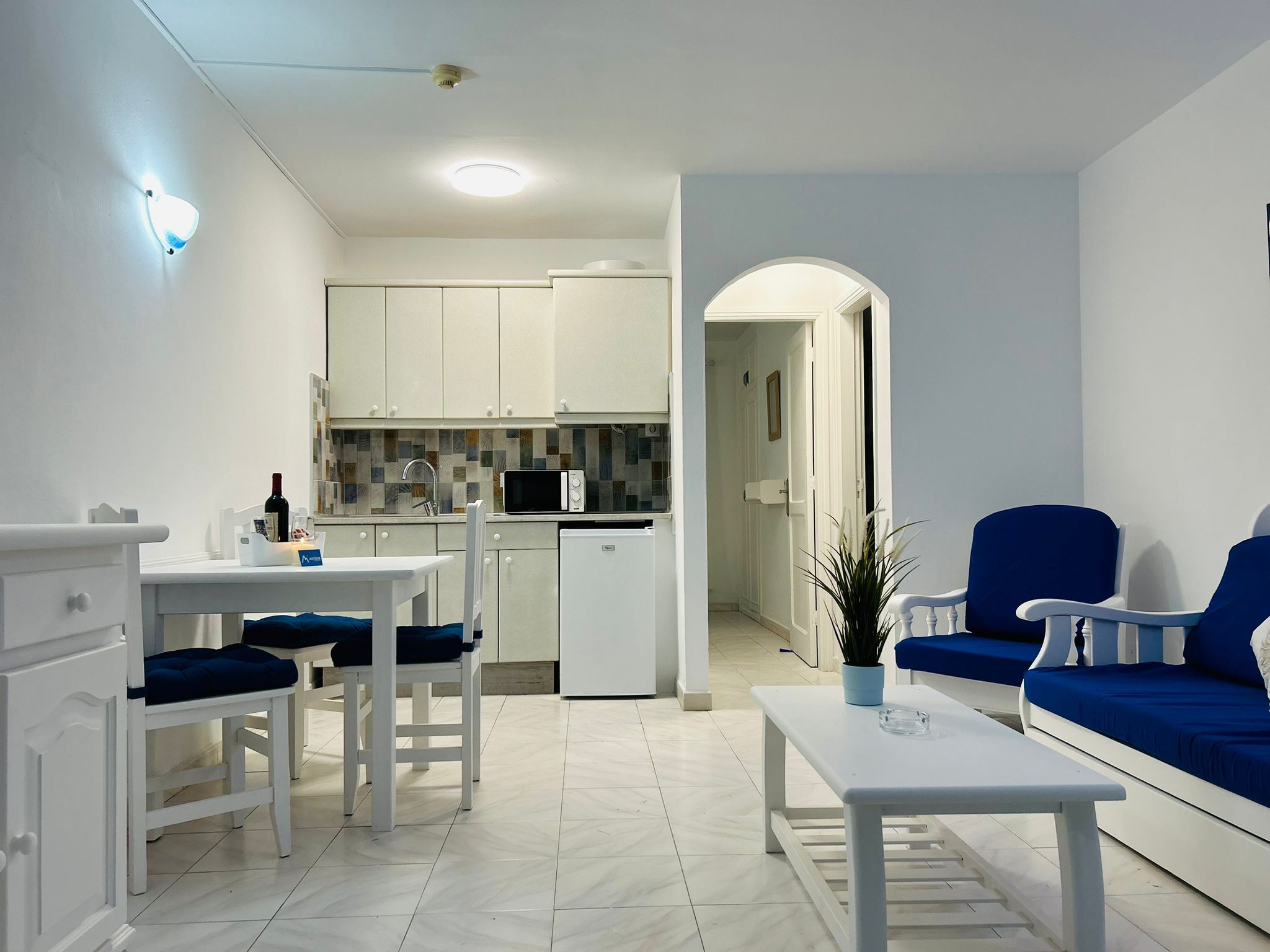 Un salon moderne avec un coin repas, une cuisine à l’arrière-plan et un canapé bleu.