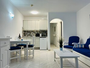 Uma sala de estar moderna com área de jantar, cozinha ao fundo e um sofá azul.