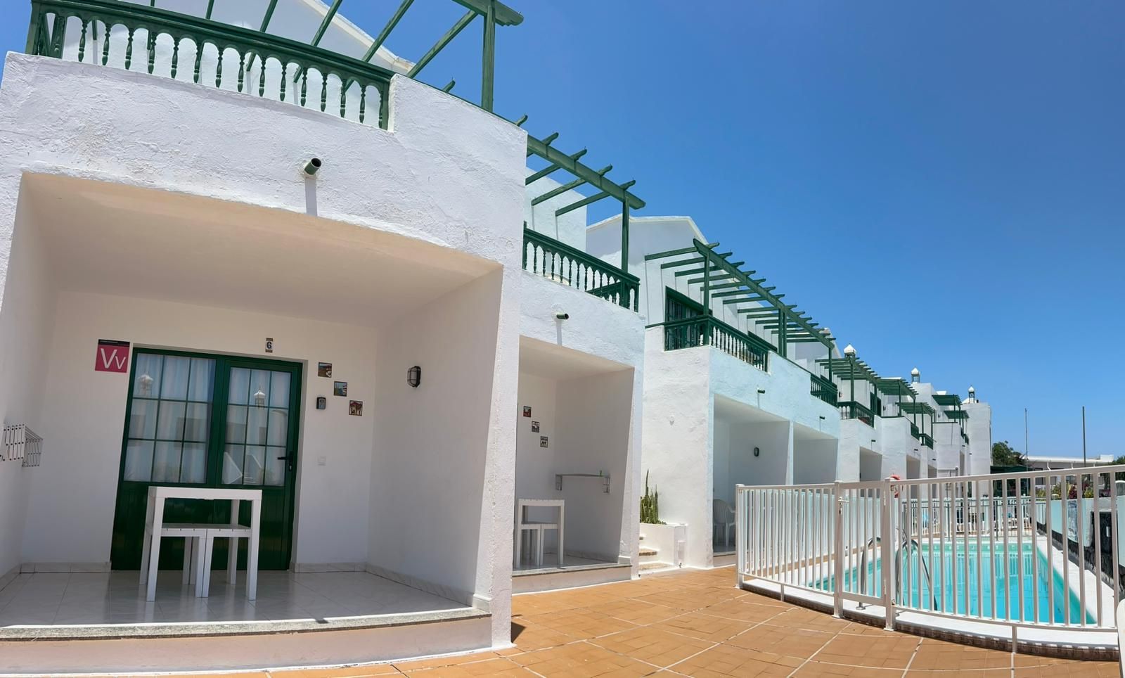 Un bâtiment blanc avec une piscine, une porte et un panneau portant une lettre.