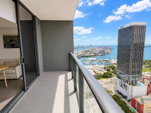 A balcony with a view of a cityscape, including a tall building with 'SKYX' on it, a marina, and a Ferris wheel. - 38th Floor 1 Bedroom Apartment with balcony & bay views in Downton Miami (Miami)