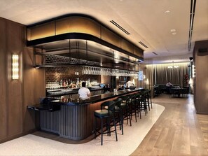 A bar area with a counter, stools, and a bartender. - 38th Floor 1 Bedroom Apartment with balcony & bay views in Downton Miami (Miami)