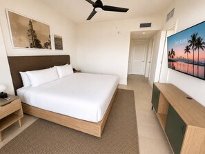 A hotel room with a large bed, a ceiling fan, a TV on the wall, and a wooden nightstand. - 38th Floor 1 Bedroom Apartment with balcony & bay views in Downton Miami (Miami)