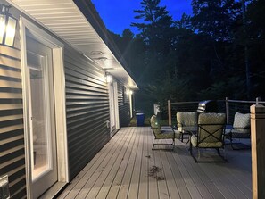 A wooden deck with outdoor furniture and a house with exterior lighting. - Private River Creek Retreat In White Mountains. Pet Friendly! (Wentworth)