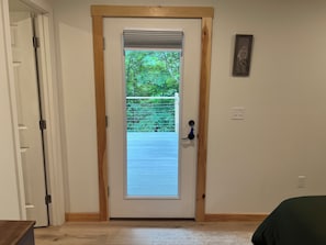 A door with a view of a balcony, a power outlet, and a framed picture on the wall.