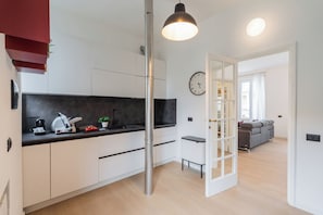 Eine moderne Küche mit weißen Schränken, einer schwarzen Arbeitsplatte und einer Edelstahl-Zwischenwand.
