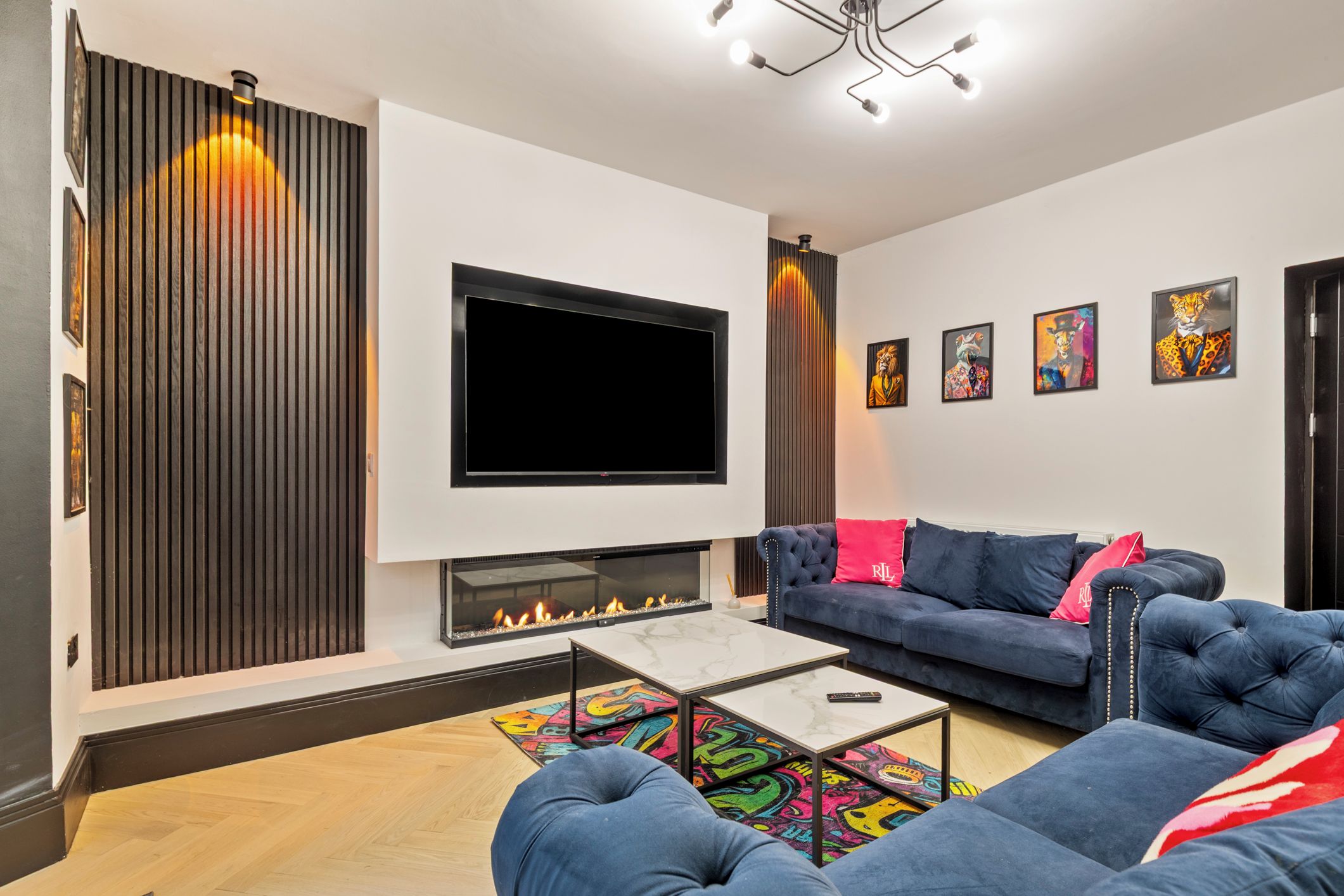 A modern living room with a flat-screen TV, a fireplace, a sofa, and a coffee table.