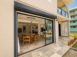 Una casa moderna con una porta scorrevole in vetro che dà su un'area pranzo con tavolo e sedie.