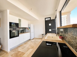 Una cucina moderna con mobili bianchi, forno nero e un piano di lavoro in marmo.