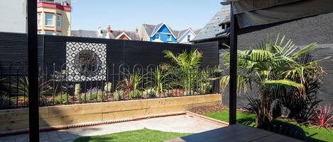 A patio area with a table and chairs, a small lawn, and a decorative metal fence.