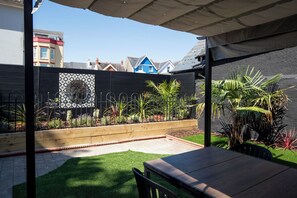 A patio area with a table and chairs, a small lawn, and a decorative metal fence. - 2 Bedford House - Close to Town and Seafront (Tenby)